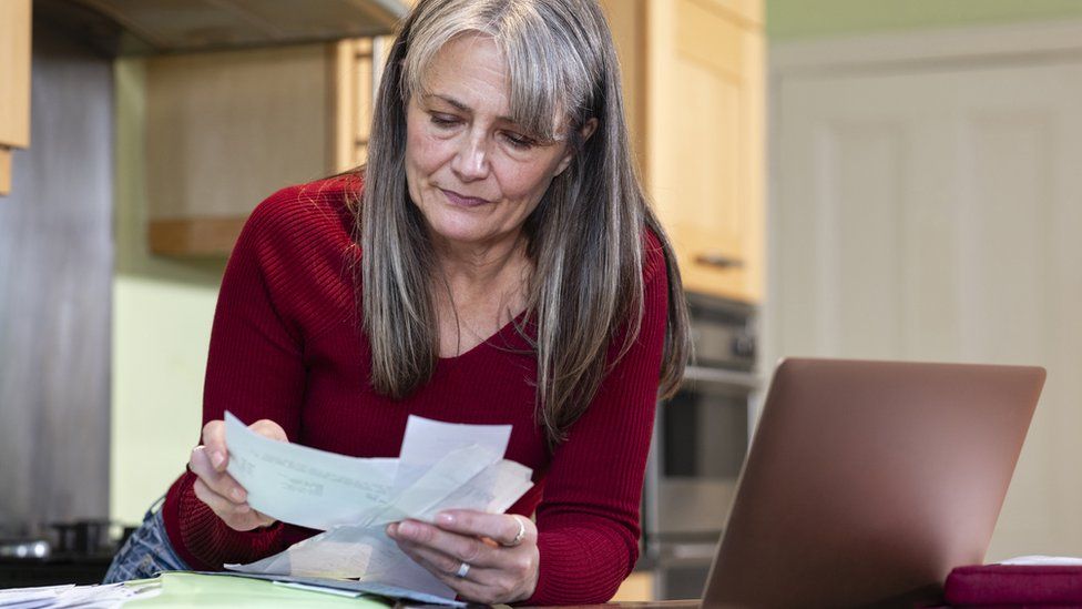 Woman looking at bills in her kitchen