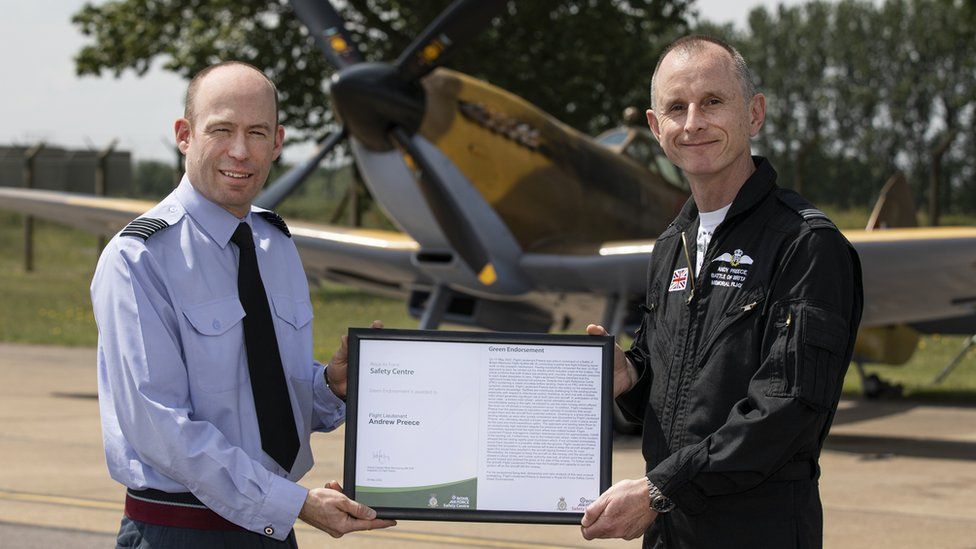 Flt Lt Andy Preece MBE (right) being presented with a Green Endorsement by Gp Capt Matt Peterson OBE, in front of Spitfire MK356
