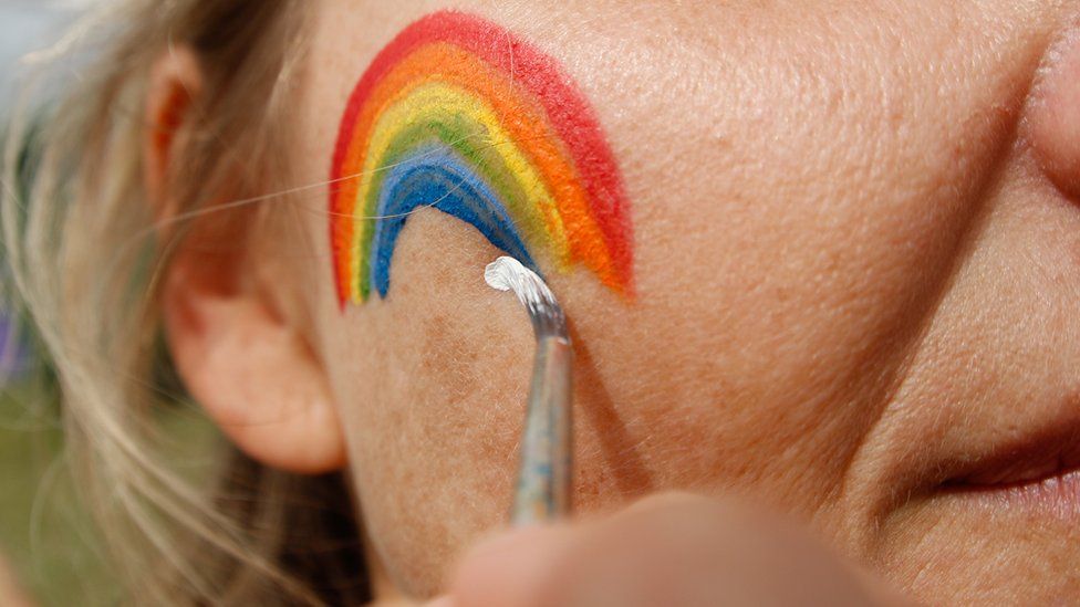 A rainbow is painted into a mature adult woman's face