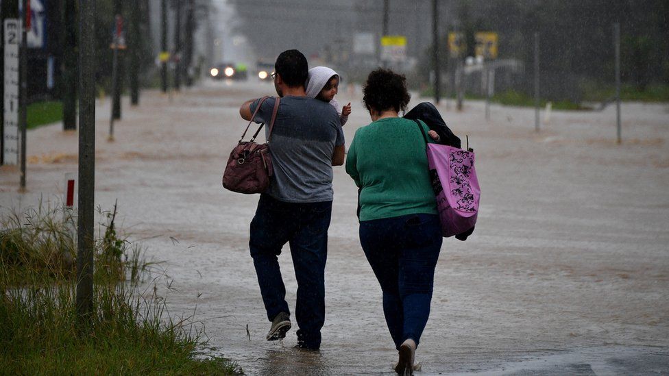 People wade through a flooded street in Sydney, Australia. Photo: 20 March 2021