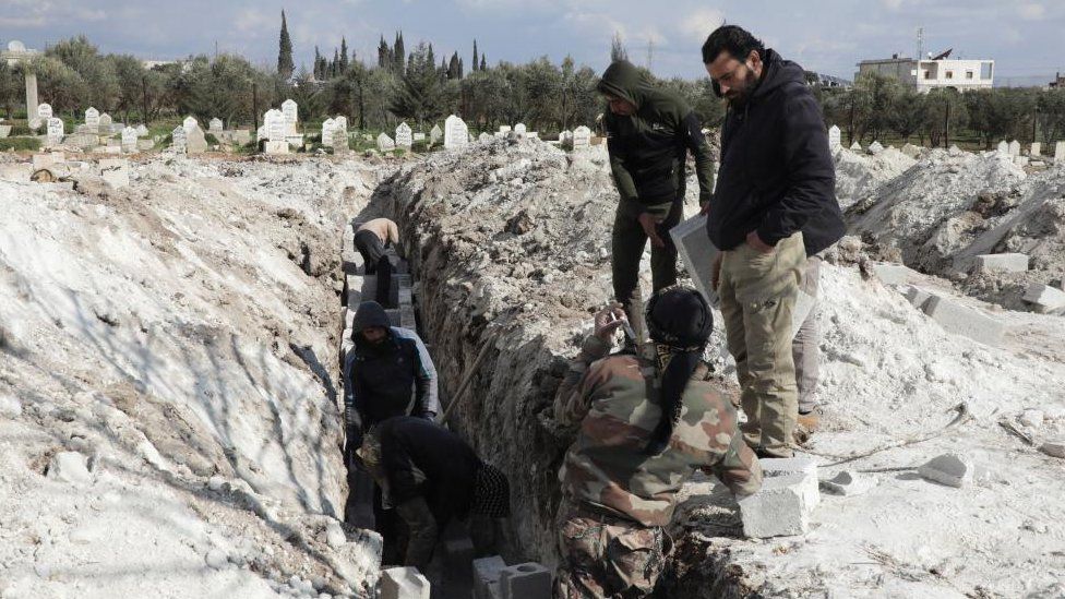 Добровольцы готовят могилы для жертв землетрясения в удерживаемом повстанцами городе Джандарис, Сирия, в пятницу