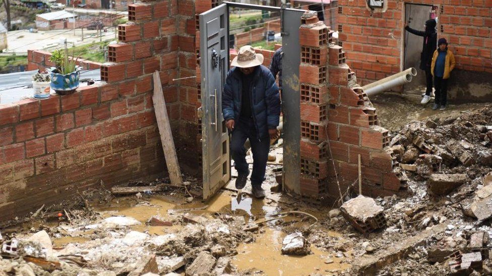 A resident passes through a door following landslides caused by rains that buried houses and left fatalities, in Achocalla, Bolivia February 17, 2024.
