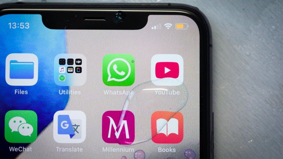 An iPhone 11 Pro Max is seen on t table covered in water droplets