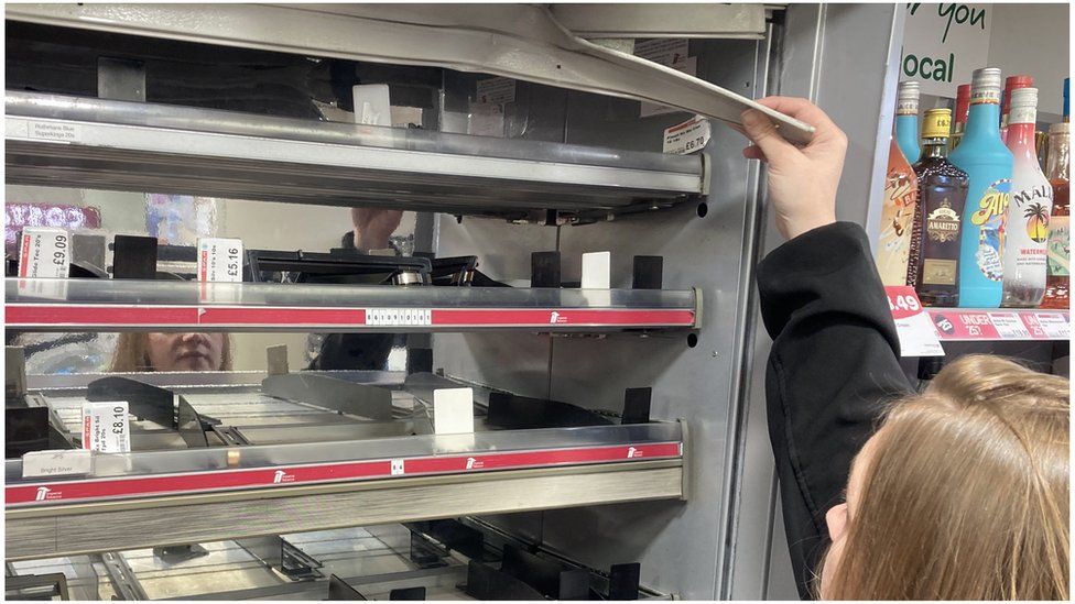 Susan Connolly reaching up to the a smashed part of the cigarette cabinet