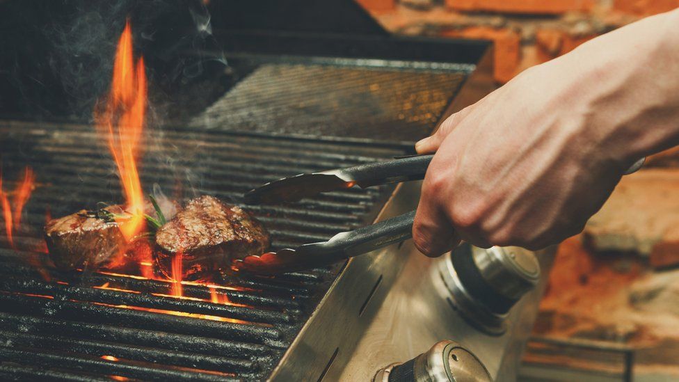 Close-up of a man cooking meat on a barbecue