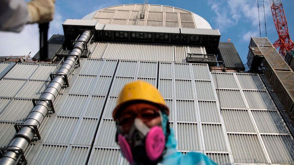 An employee of Tokyo Electric Power Company stands in front of the company's reactor number 3 at Fukushima Daichi nuclear power plant in Fukushima prefecture.