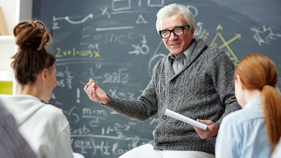 Stock image of a male physics or maths teacher talking to female school students