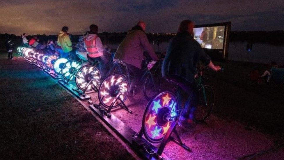 A group of people sitting on bikes with flashing lights in the wheels