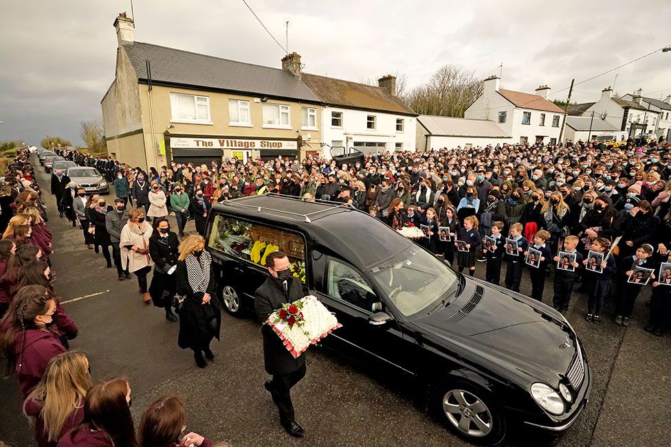 Скорбящие идут рядом с катафалком, когда кортеж прибывает в церковь Святой Бригитты, Маунтболус, графство Оффали, Ирландия, на похороны Эшлинг Мерфи, 18 января 2022 г.