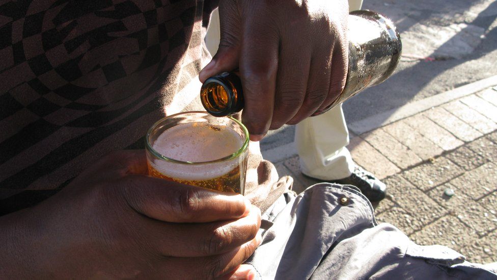 A man pouring a beer at a shebeen in South Africa