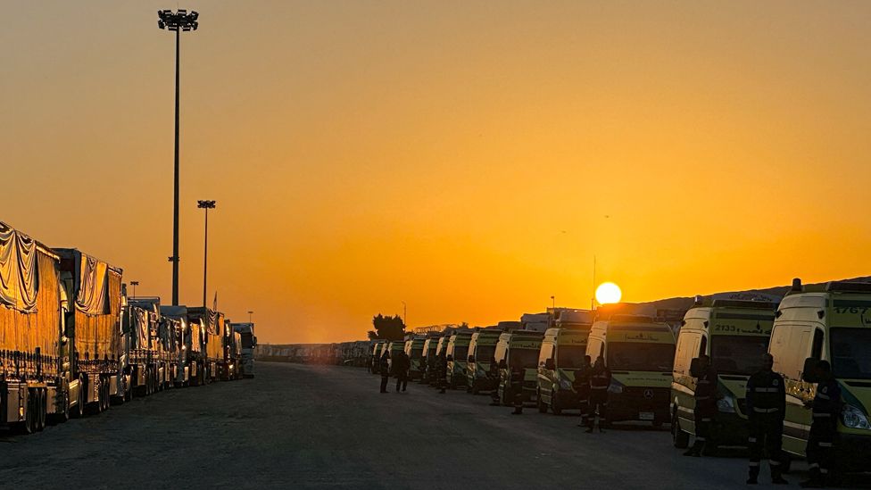 The sun seen behind lines of ambulances and lorries at Egypt's Rafah crossing waiting to enter the Gaza Strip - Monday 11 December 2023