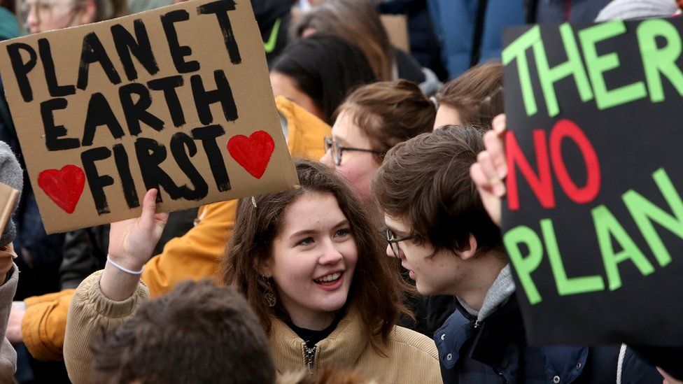 a young woman holds up a sign reading "Planet Earth First" at a demonstration against climate change in Hamburg