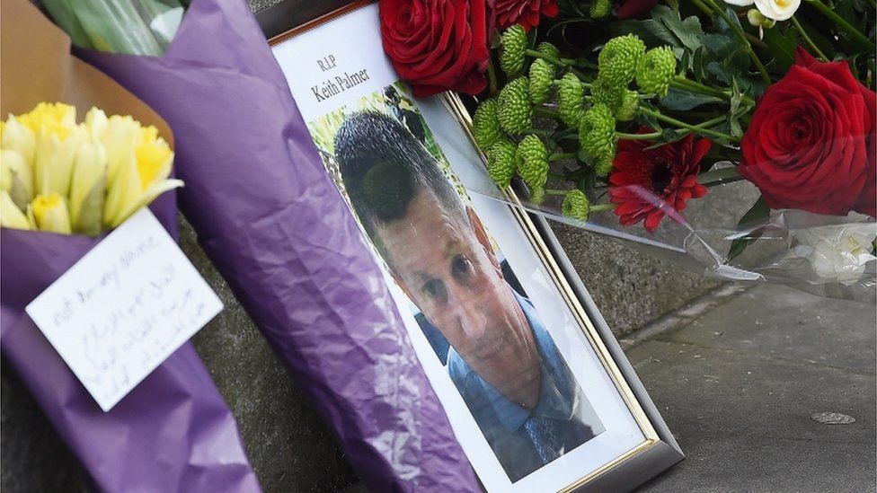 A photograph of policeman Keith Palmer who was killed in the terror attack is placed on Whitehall with flowers