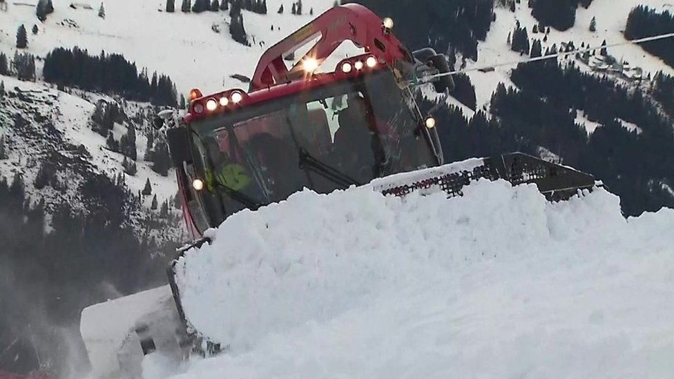 A plough moves snow up a slope in Wengen