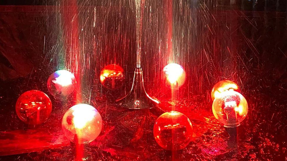 Fountain surrounded by glass balls lit up in orange and red