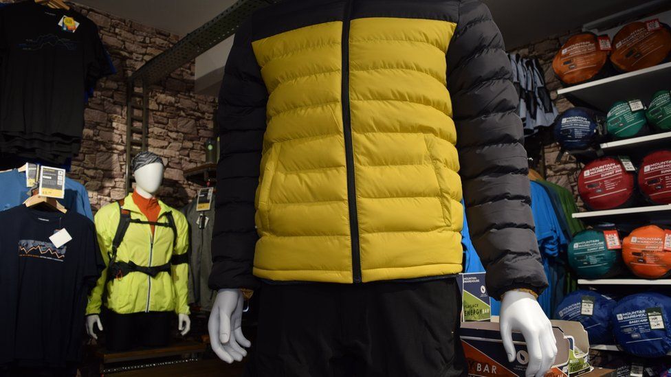 A yellow jacket in the foreground of a Mountain Warehouse shop