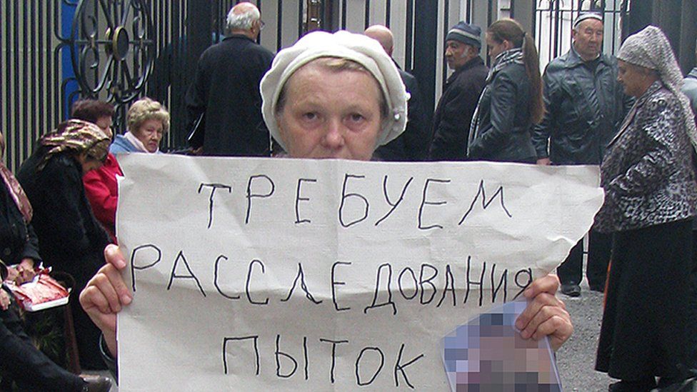 Elena Urlaeva holds up poster saying "We demand an investigation into torture"