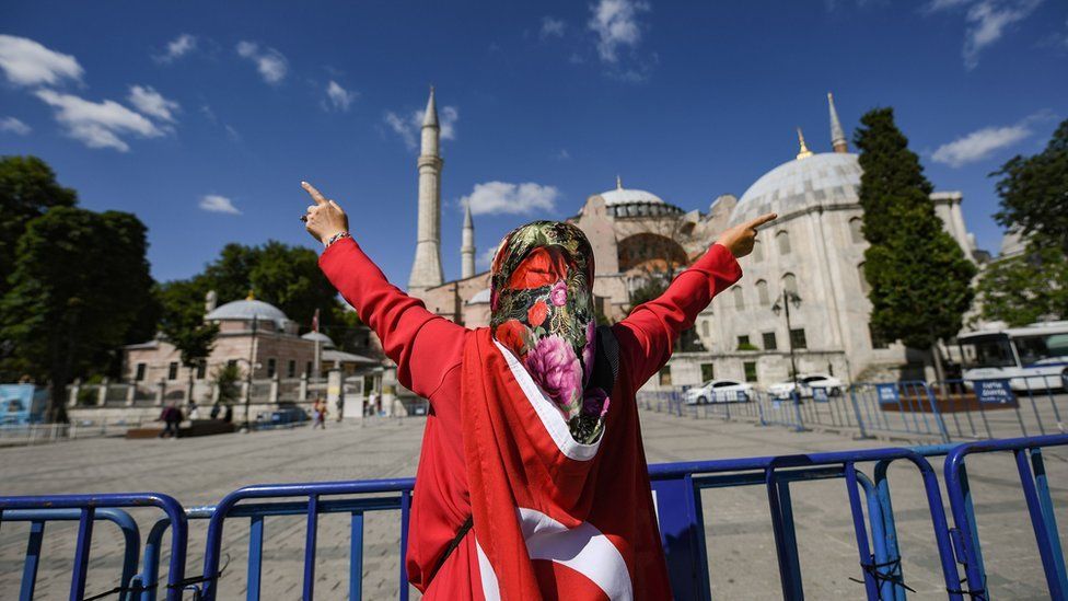 A woman wrapped in a Turkish national flag gestures outside the Hagia Sophia museum on July 10, 2020 in Istanbul as people gather to celebrate after a top Turkish court revoked the sixth-century Hagia Sophia"s status as a museum, clearing the way for it to be turned back into a mosque
