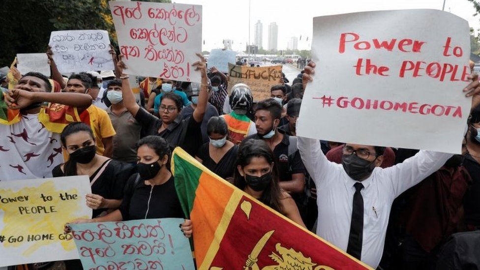 Протестующие держат плакаты с призывом к отставке президента Раджапакса возле парламента в Коломбо