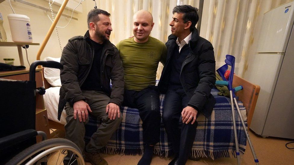 Rishi Sunak and Volodymyr Zelensky meet a wounded war veteran during a visit to a hospital in Kyiv