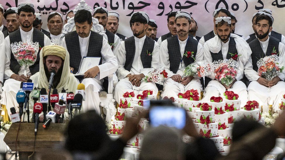 Afghan grooms look on during a mass wedding ceremony at a wedding hall in Kabul