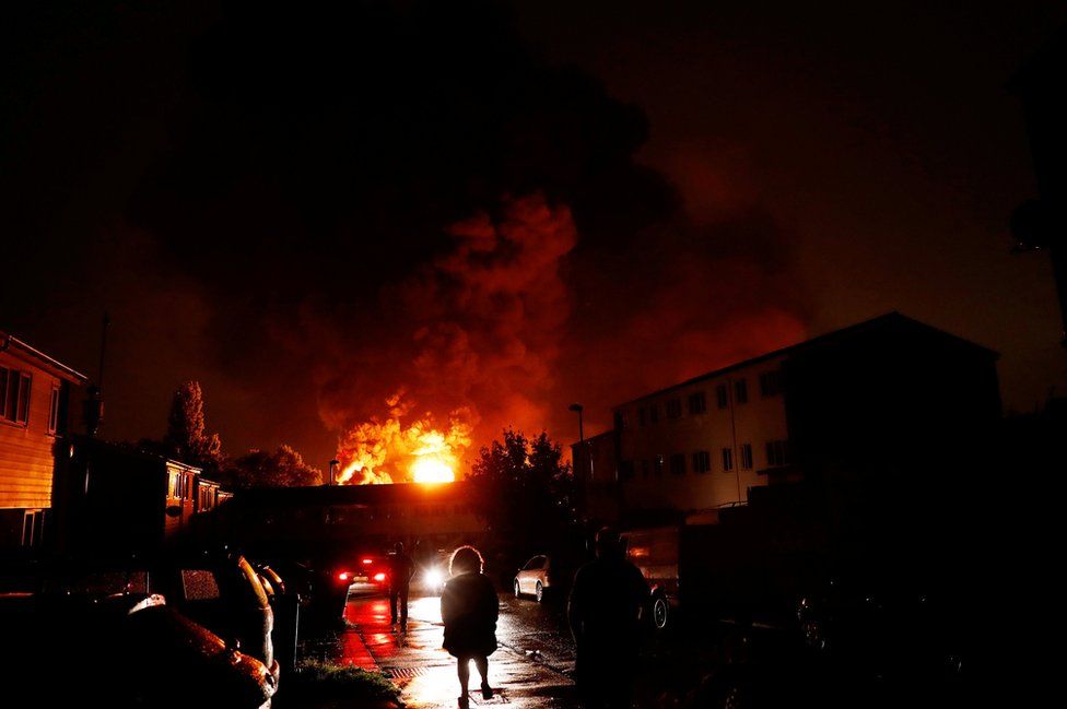 People watch as smoke billows from a fire at a warehouse in Tottenham, north London