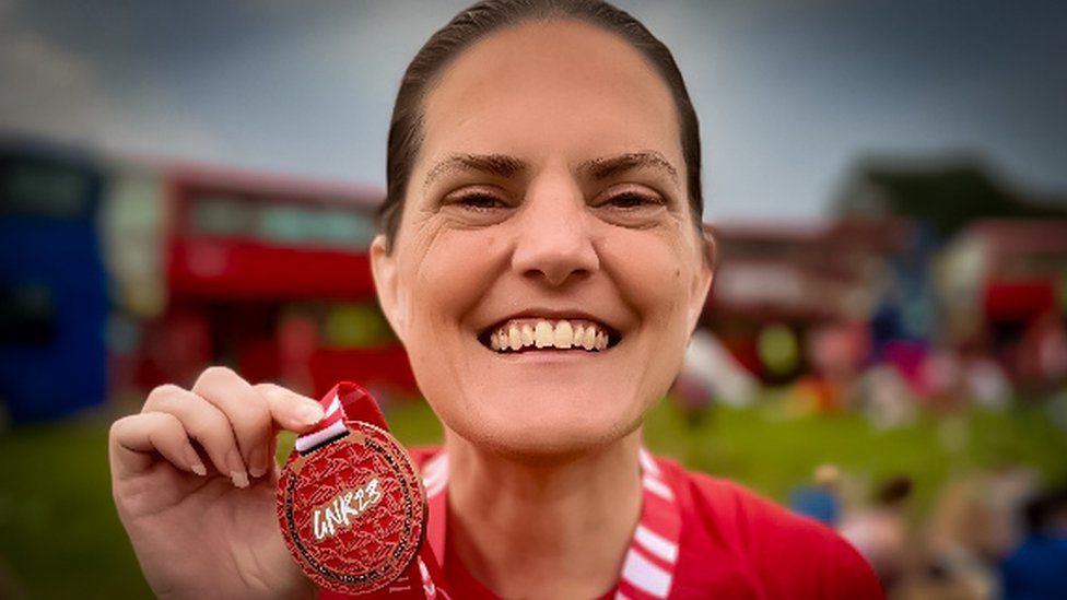 Gayle Redman holding a medal at a competitive race