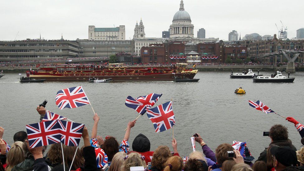 Onlookers cheer on the Queen's barge on the Thames