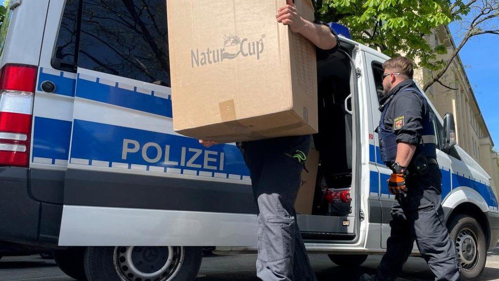 Police officers carry boxes into a police building in Mainz, Germany, May 3, 2023
