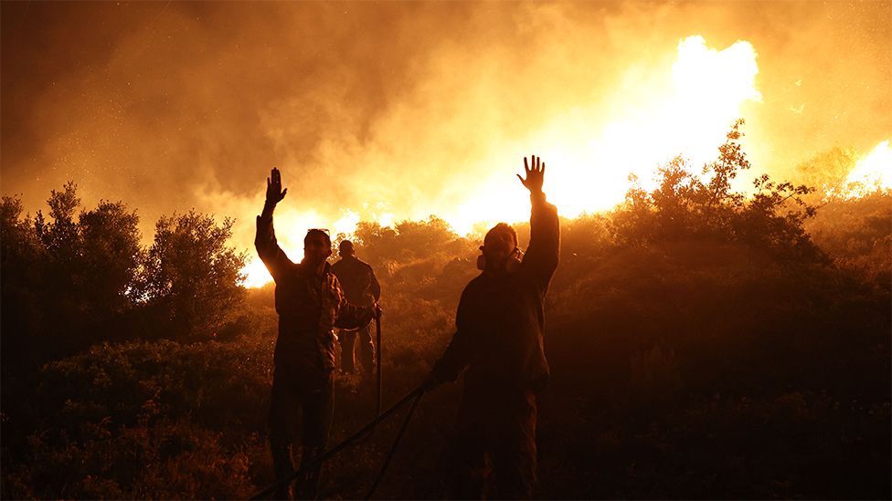 Firefighters gestures as they work to extinguish a wild fire