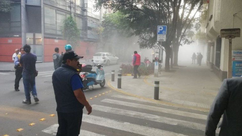 Clouds of dust are seen in the air as residents gather on the streets of Mexico City