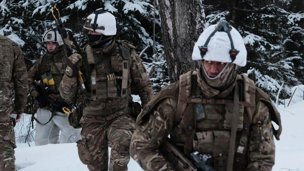 Four British Army soldiers on a military exercise in Estonia, they are in full camouflage gear in the snow and carrying rifles