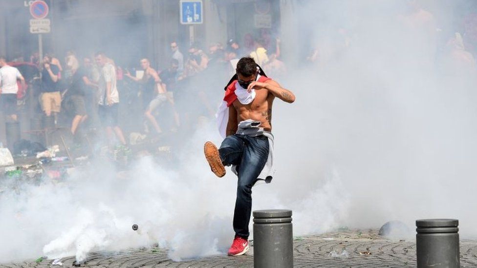 England fan kicks a can of tear gas away