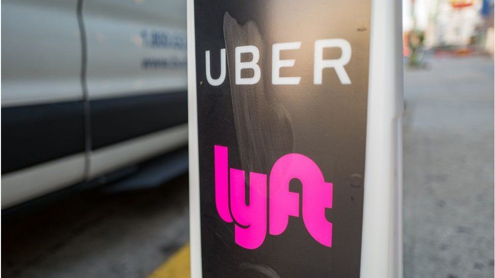 Uber and Lyft logos by a taxi