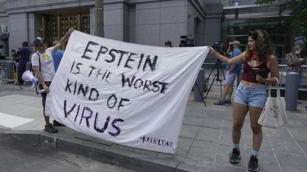 Protesters hold a sign against Epstein during a 2020 bail hearing for Maxwell