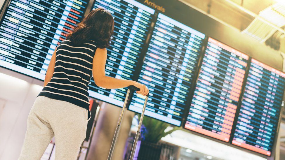 Woman standing in front of departure board