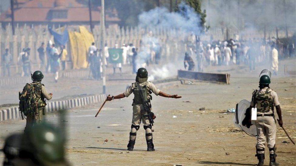 An Indian policeman gestures towards Kashmiri demonstrators during a protest after Eid al-Adha prayers in Srinagar, September 25, 2015.