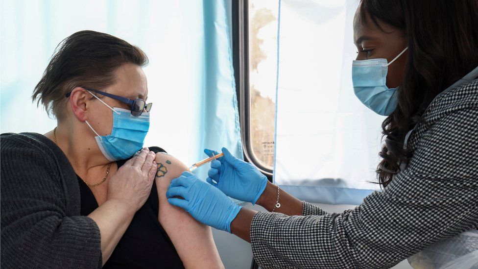 A woman receives a dose of the Oxford-AstraZeneca COVID-19 vaccine inside a bus modified into a mobile vaccination centre for the coronavirus disease (COVID-19), in Thamesmead, London