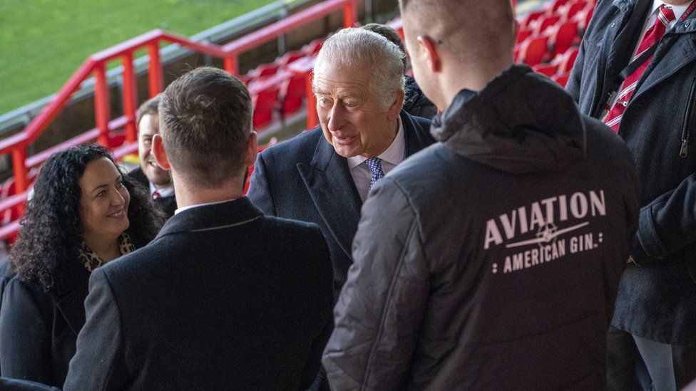 King Charles III (centre) during a visit to Wrexham Association Football Club's Racecourse Ground. King Charles III and the Queen Consort met owners and Hollywood actors, Ryan Reynolds and Rob McElhenney, and players to learn about the redevelopment of the club, as part of their visit to Wrexham. Picture date: Friday December 9, 2022. PA Photo. See PA story ROYAL King. Photo credit should read: Arthur Edwards/The Sun/PA Wire