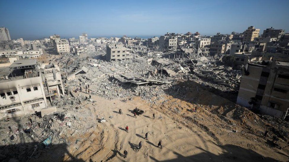 Palestinians walk across a rubble-strewn area after Israeli forces withdrew from Gaza's Al Shifa Hospital