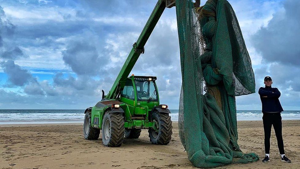 tractor lifting fishing net on beach
