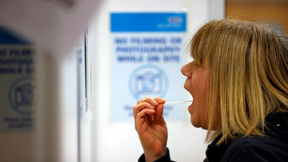 A woman carries out a swab test in west London