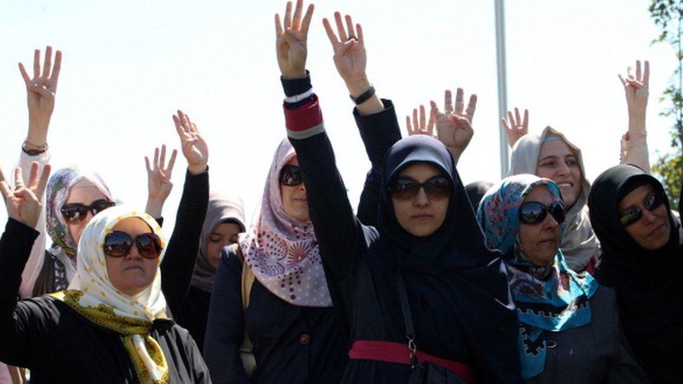 Turkish demonstrators raise their hands during a protest organised by pro-Islamic groups outside the Middle East Technical University in Ankara (07 September 2013)