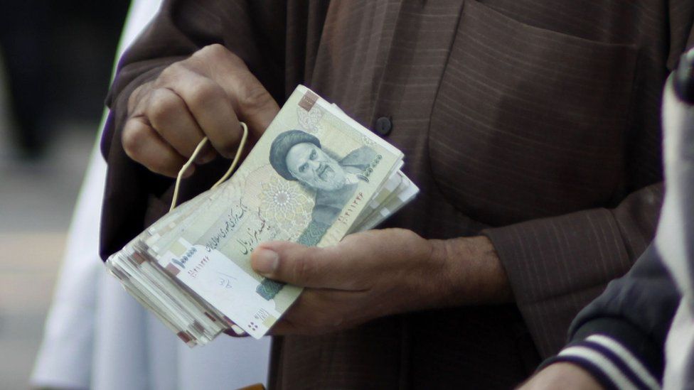 A man's hands holding Iranian rial