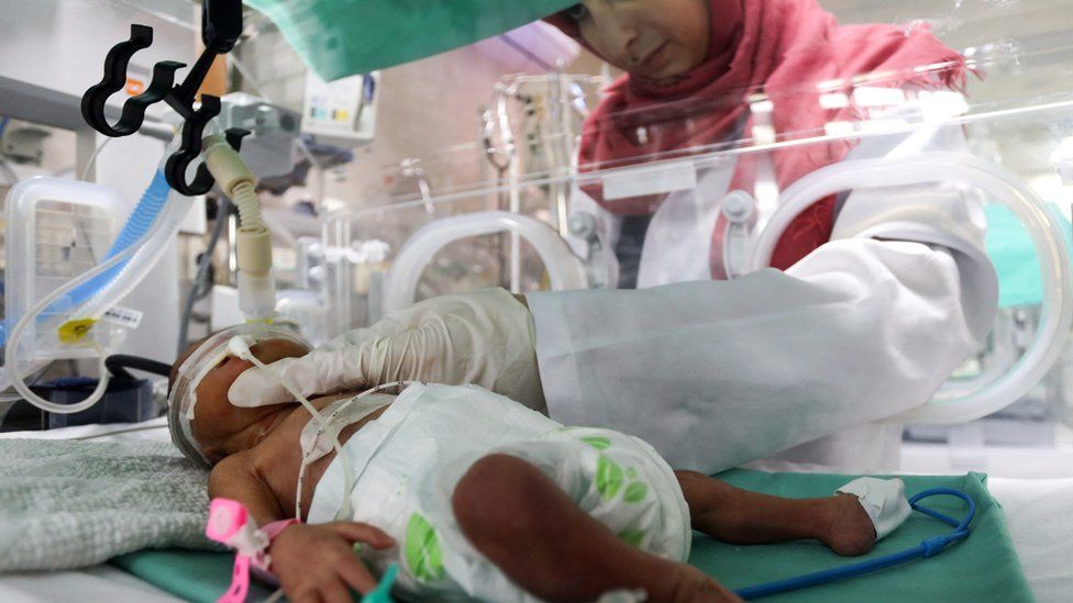 A medical worker assists a premature Palestinian baby lying in an incubator at the maternity ward of al-Shifa Hospital, in Gaza City (22 October 2023)