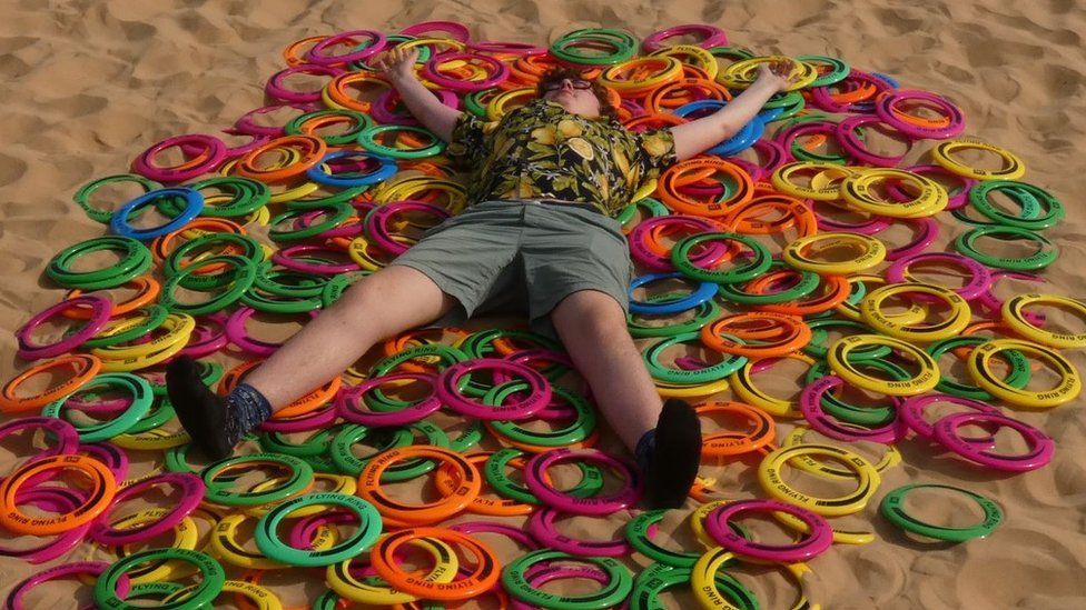 Boy lying on plastic ring toys