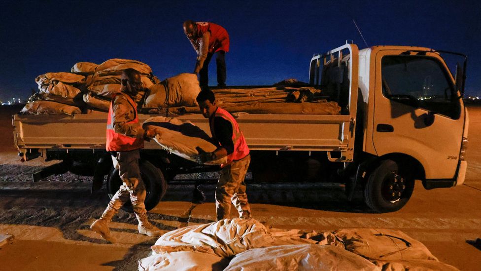 Three men load a truck with aid for Syria