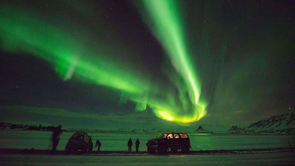 Tourists photograph the Northern Lights in Iceland