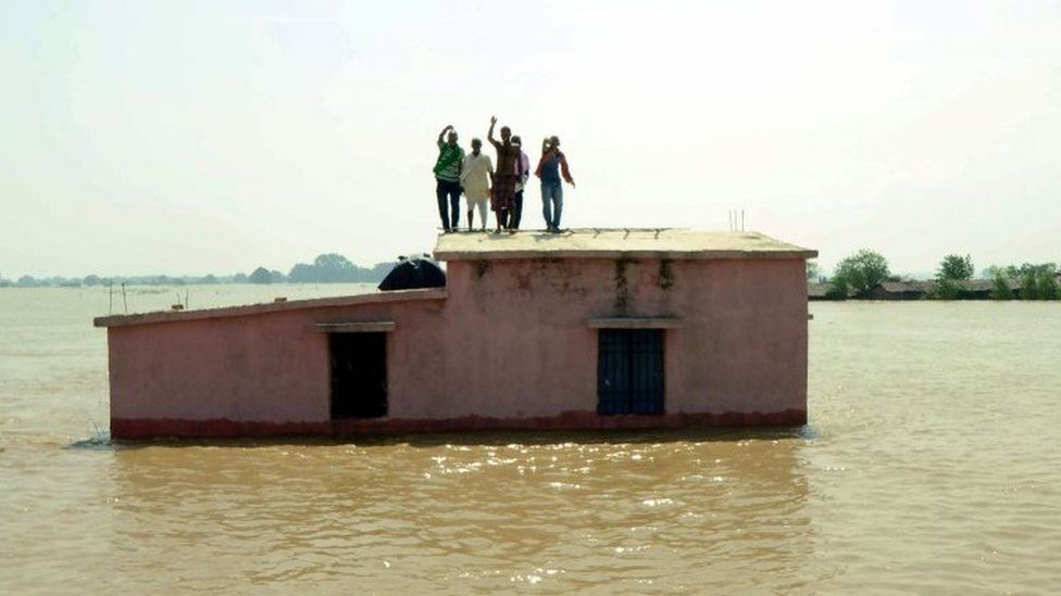 Flood affected people stand on the roof of a submerged house as they wait to be rescued at Kasimpurchak, near Danapur Diara in Patna in eastern Bihar state.