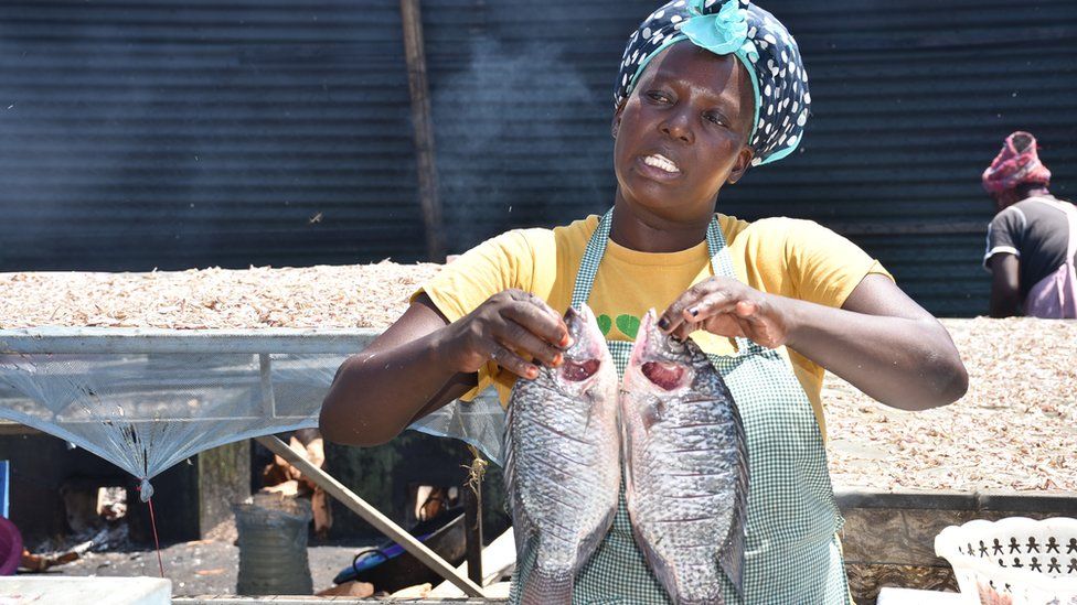 Esther Ongowe holds fish at the Dunga beach fish market in Kisumu